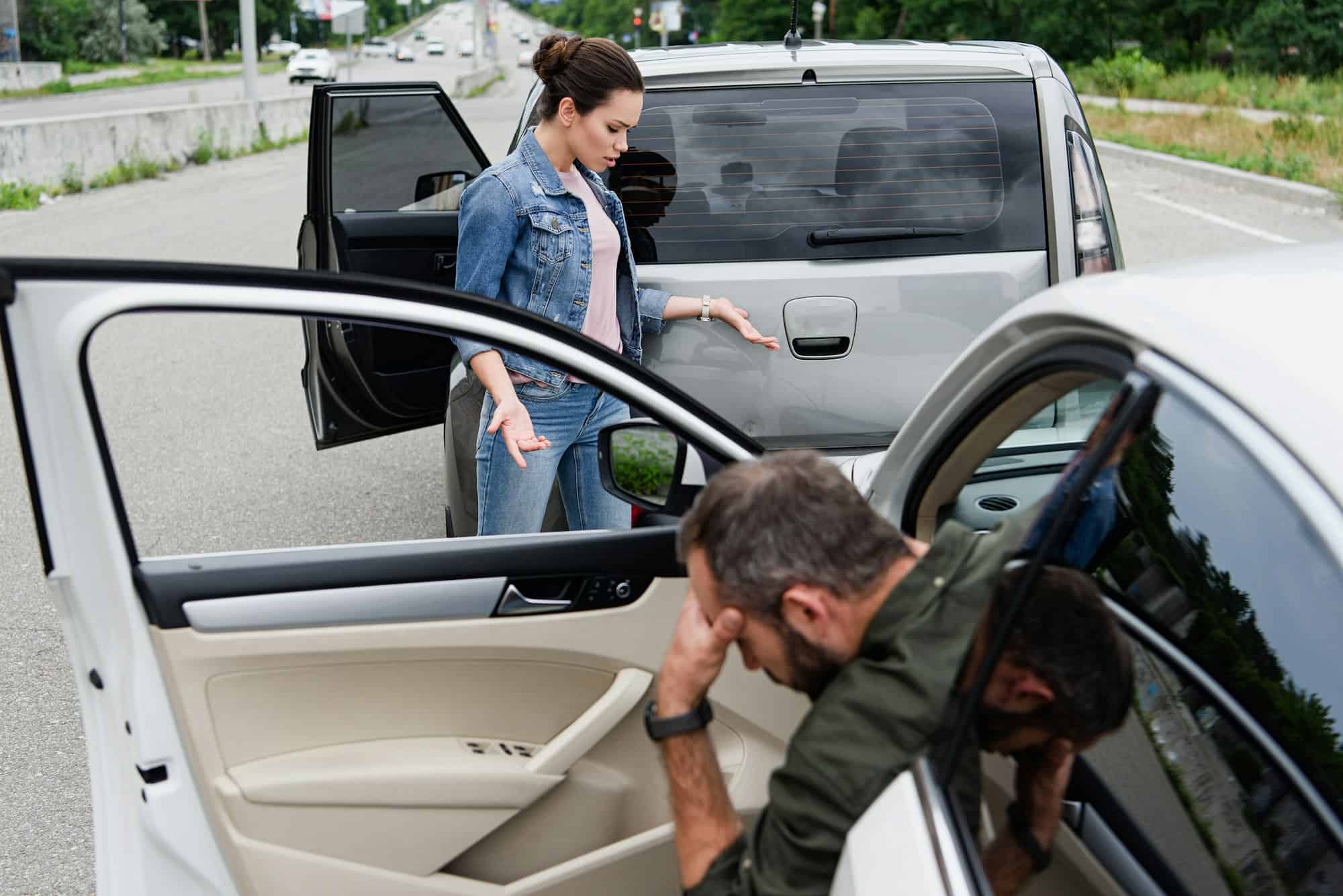 female driver looking at cars after car accident on road